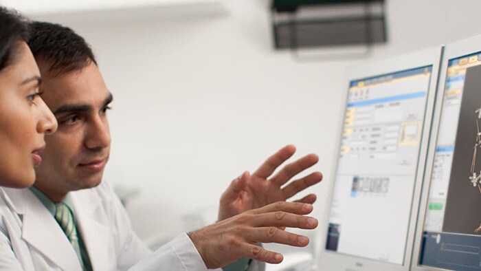 Imagem de médicos a discutir os resultados da TC num monitor de computador