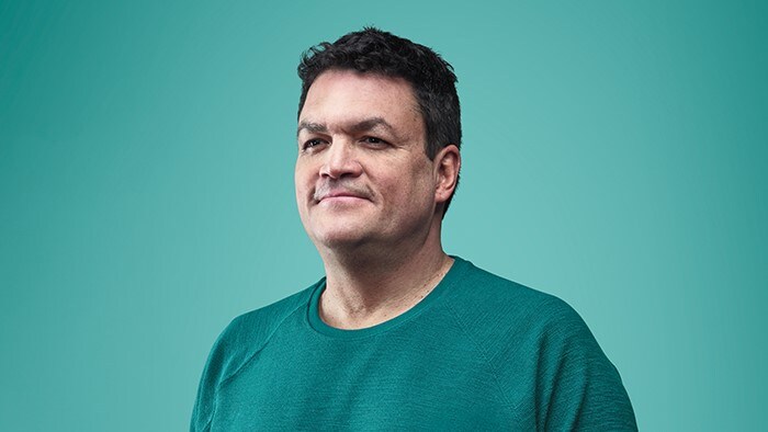 Imagem de um homem sorrindo usando uma camiseta verde