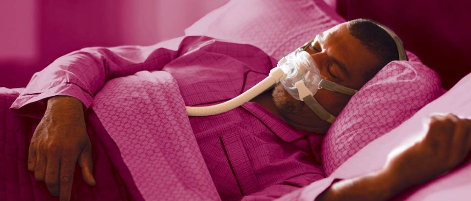 Homem com roupa cor-de-rosa dormindo com uma máscara