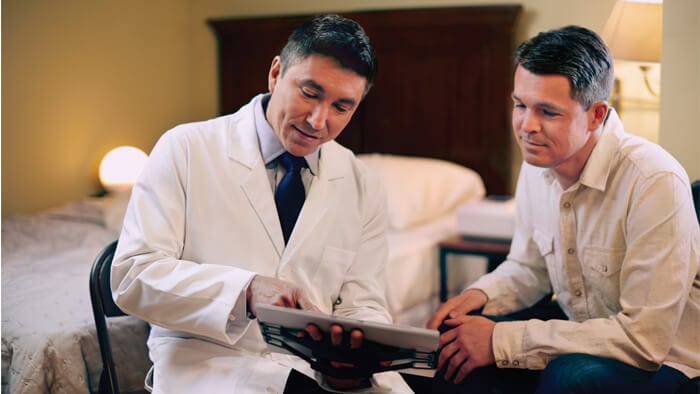 Fotografia de m&eacute;dico apresentando resultados em um tablet a paciente do sexo masculino